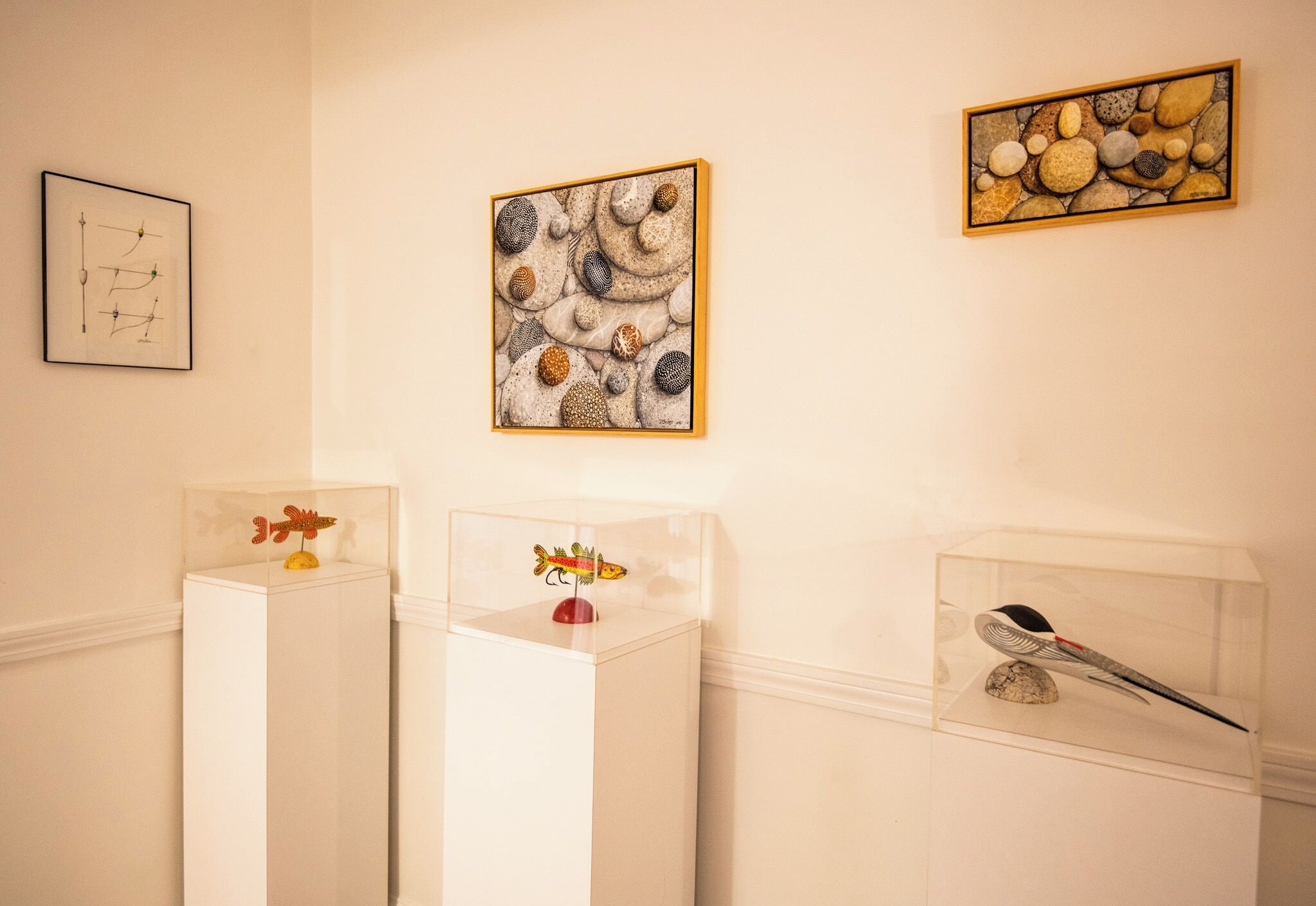 Une galerie où sont exposées des œuvres d’art, notamment un tableau abstrait encadré et une sculpture présentée dans une vitrine transparente.