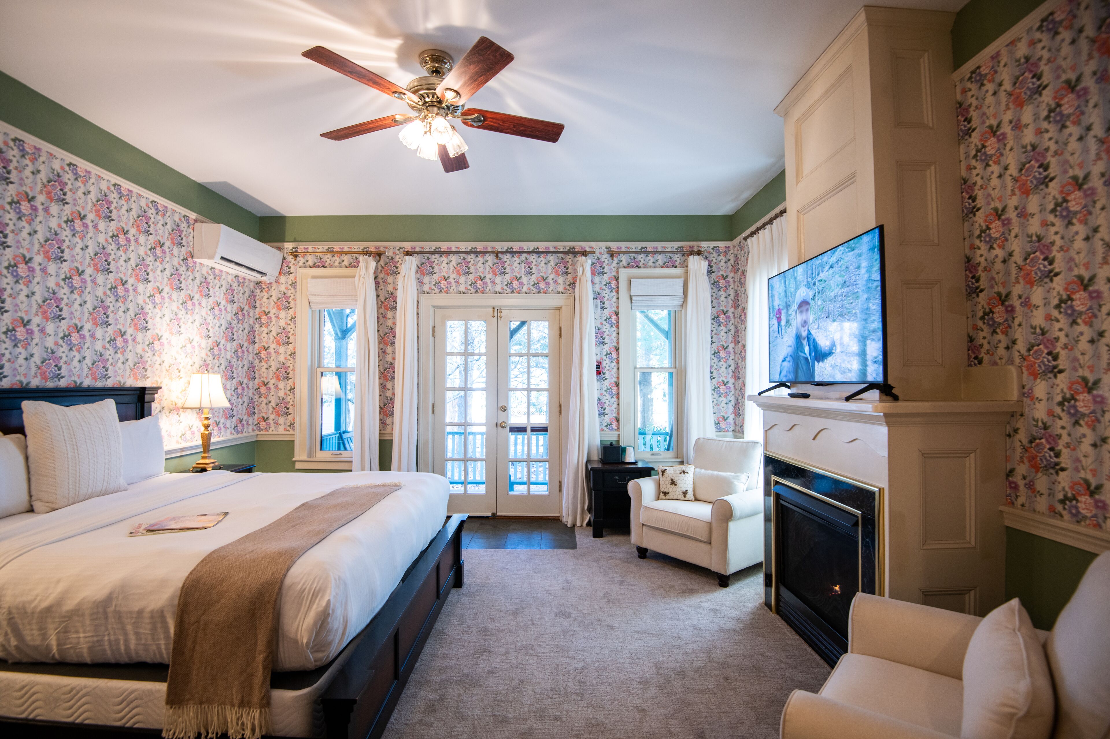 A bedroom with a bed, a chair, a fireplace, and a television.