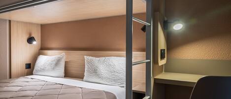 A bunk bed with a headboard, a bedside table, and a wall-mounted light fixture.