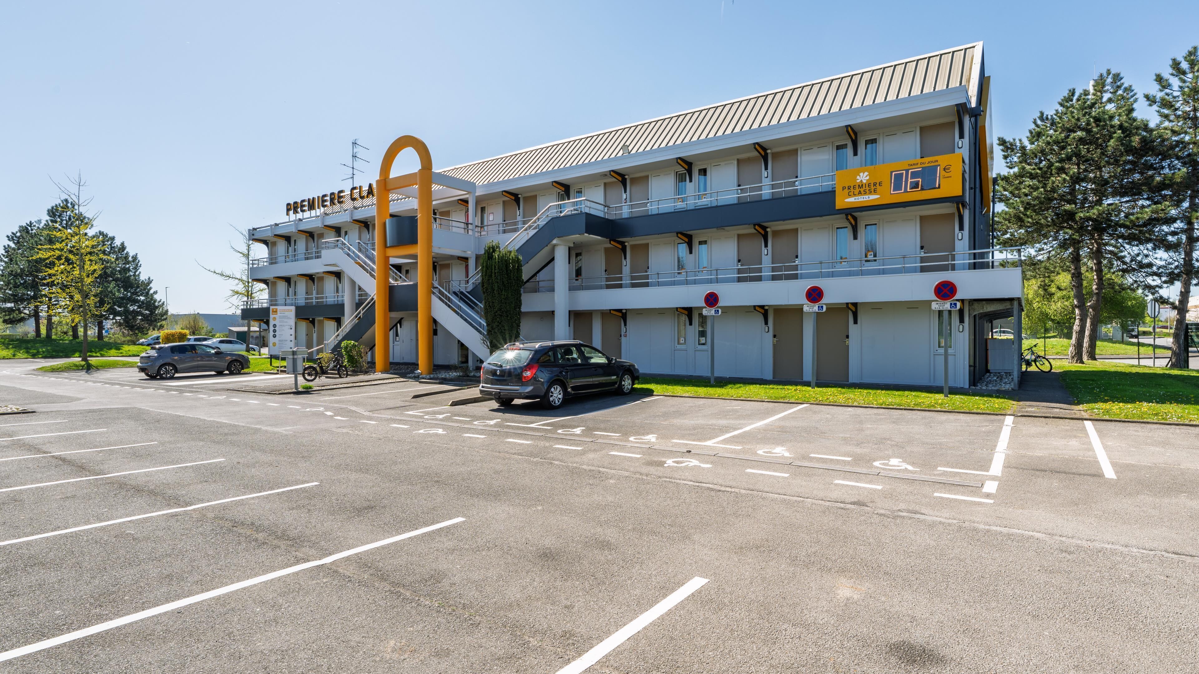 A multi-story hotel with a prominent entrance, a parking lot, and a clear sky.