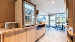 Una cocina moderna con refrigerador integrado, armarios de madera y un área de estar con mesas y sillas.