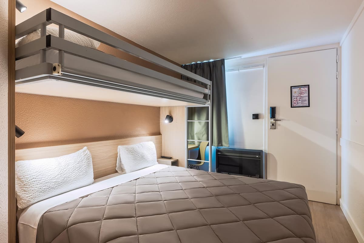 Een hotelkamer met een bed, een bureau, een stoel, een kledingkast en een deur.