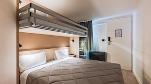 Quarto de hotel com cama, escrivaninha, cadeira, guarda-roupa e porta.