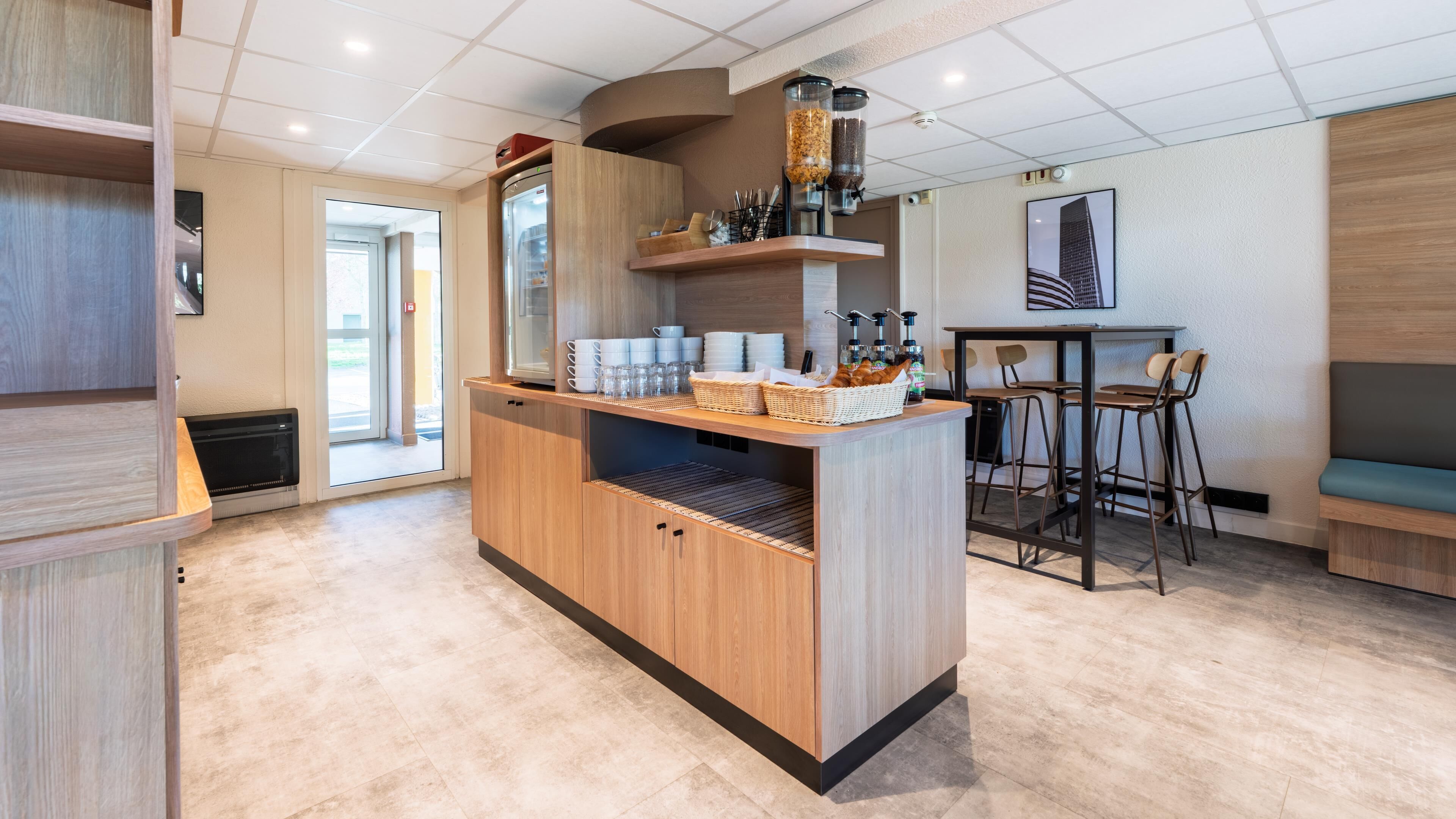 A modern kitchen area with a central island, bar stools, and a seating area.