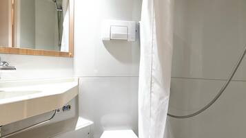 Een badkamer met een wit wastafel, een spiegel, een douche en een handdoekhouder.