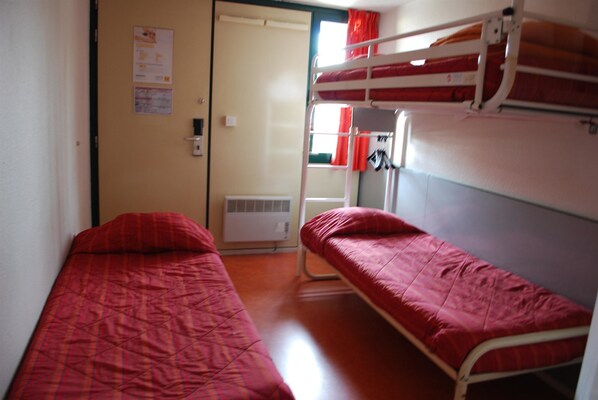 Un dormitorio con literas, un radiador y una puerta que da a otra habitación.