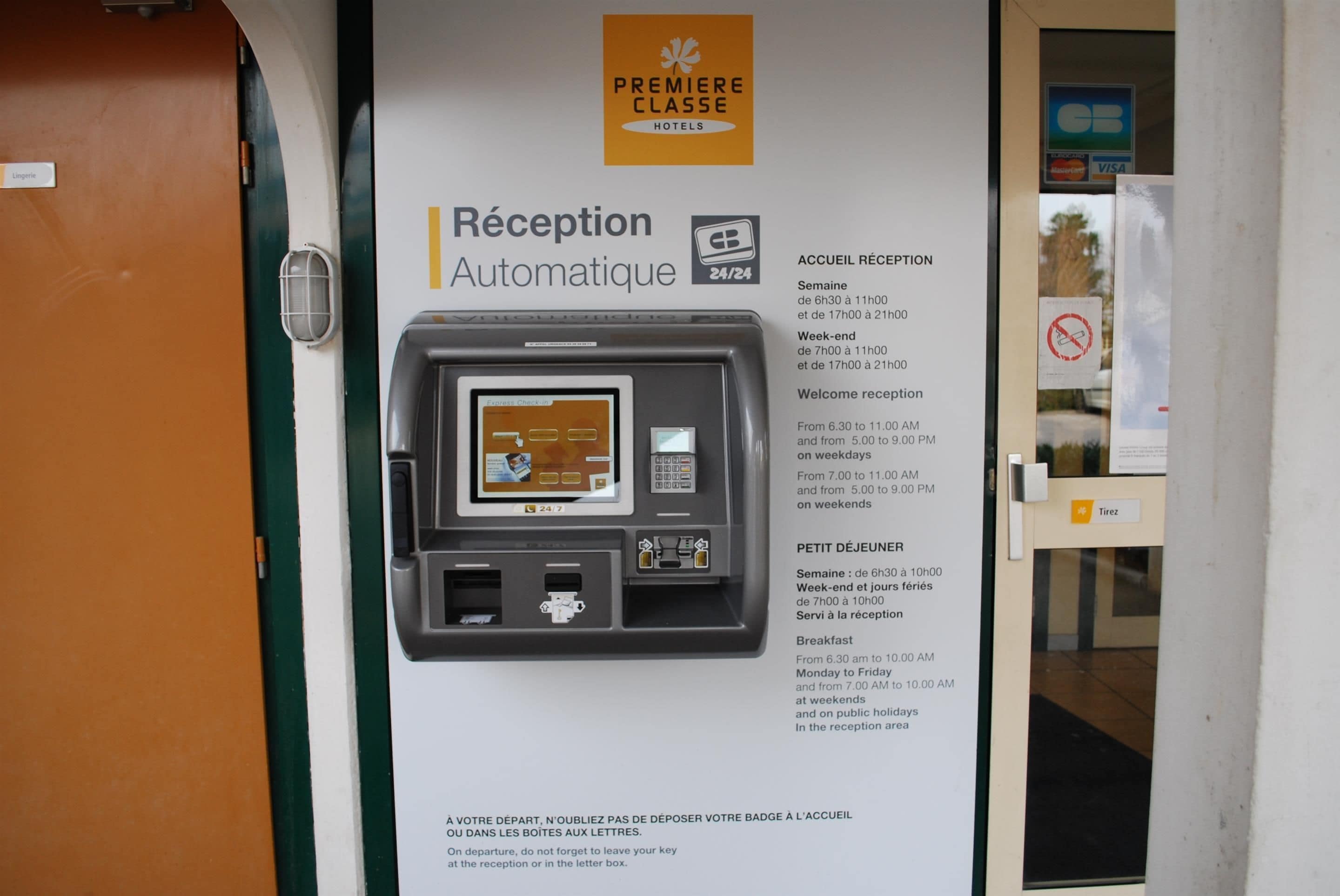A hotel reception area with an automatic reception machine, a sign for Premier Classe Hotels, and a notice about reception hours.