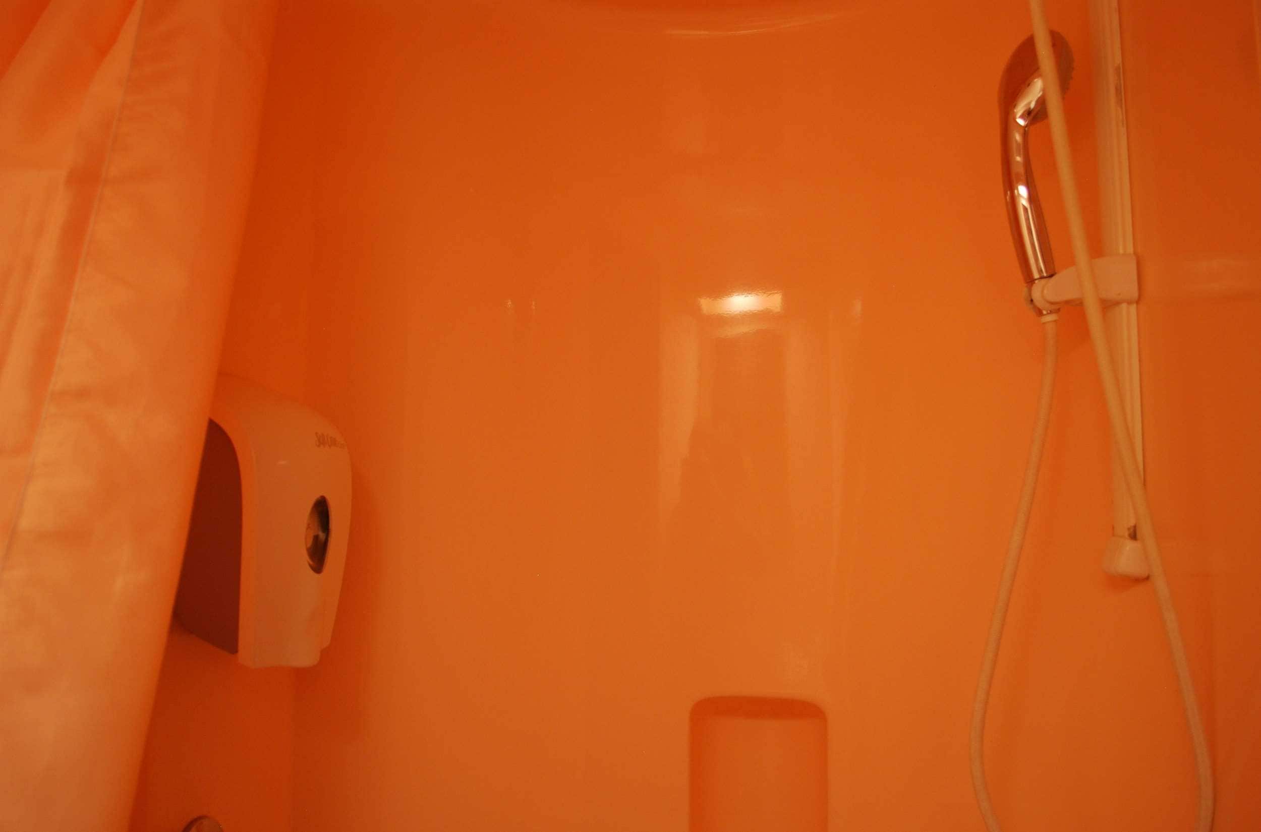 Un baño con cortina de ducha blanca, cabezal de ducha de mano y dispensador de jabón.