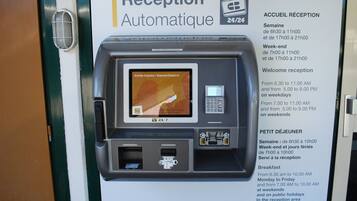 Een receptie kiosk met een scherm waarop 'Arrivée Express / Express Check-In' staat en een keypad.