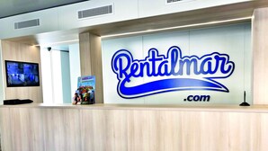 Un comptoir d’accueil avec une grande enseigne indiquant « Rentalmar.com ».