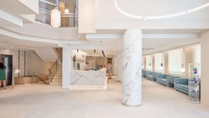 A spacious lobby with a marble column, seating area, and a reception desk. - Hotel Best Mediterraneo (Salou)