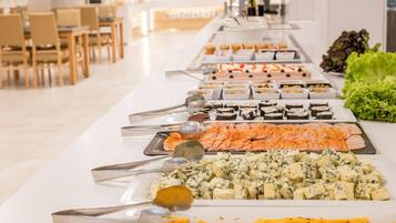 A buffet table with various food items including sushi, cheese, and salads.