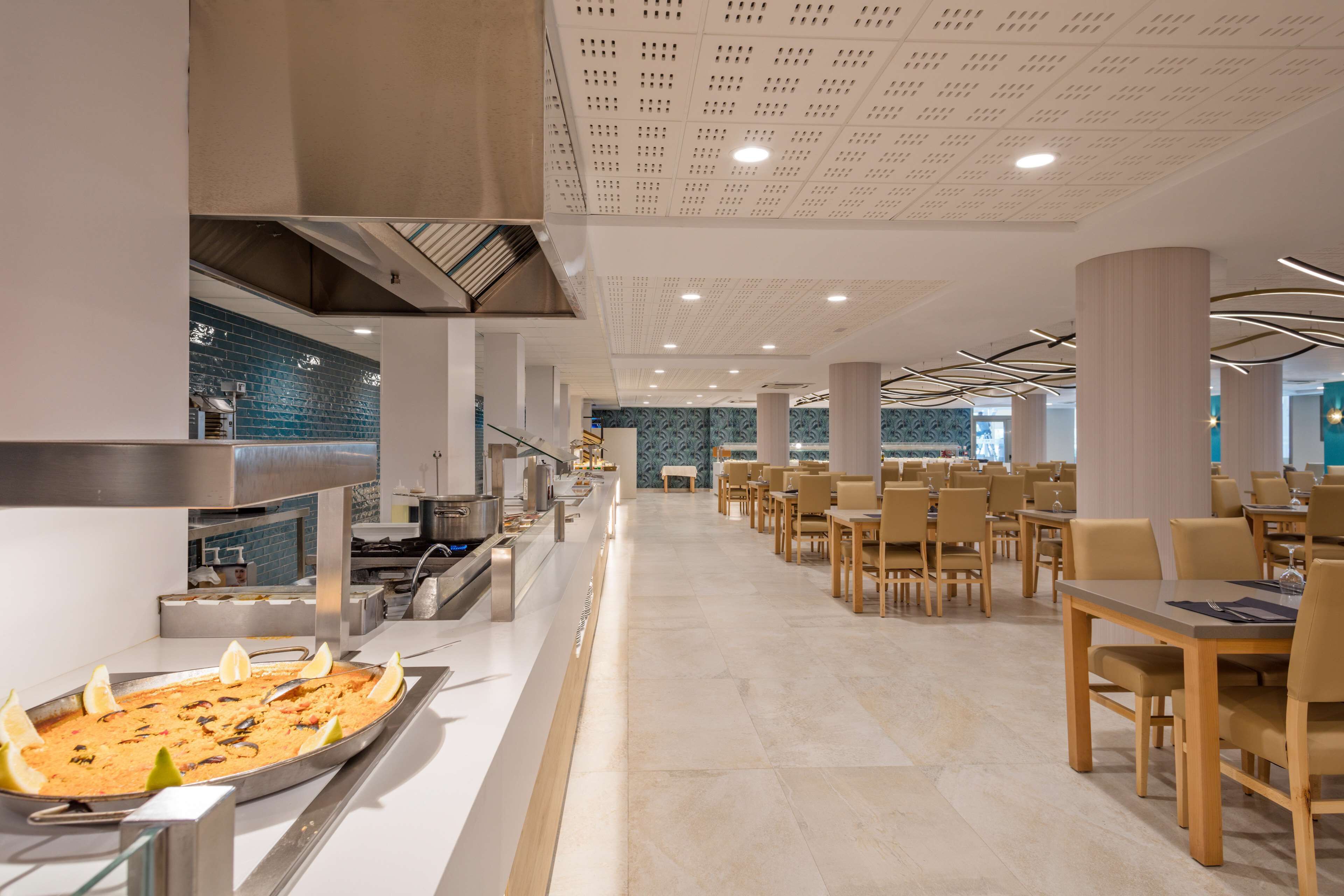 A spacious restaurant with a long counter, multiple tables, and a central serving area.