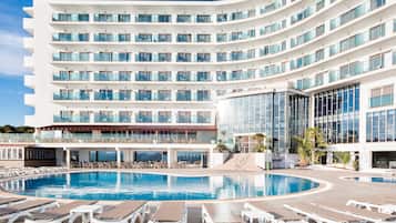 Un hotel moderno con un amplio espacio de piscina, varios balcones y vista despejada al océano.