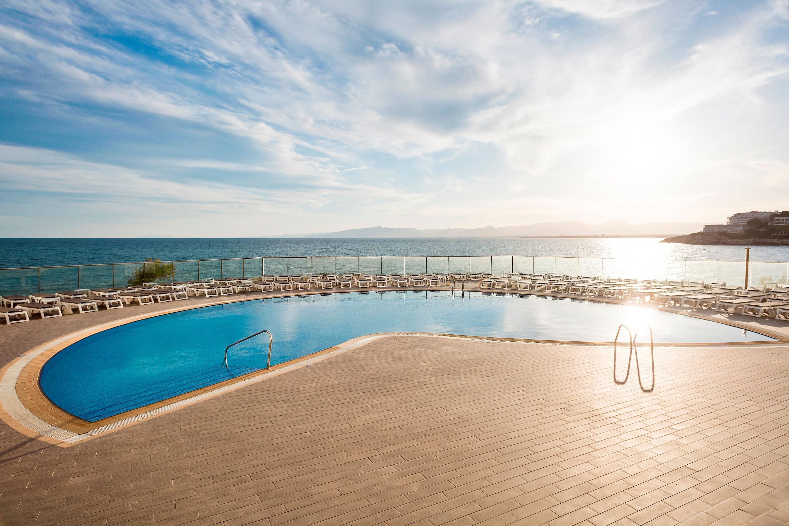 Une piscine avec vue sur la mer et les montagnes en arrière-plan.