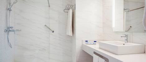 A modern bathroom with a walk-in shower, a white sink, and a large mirror.