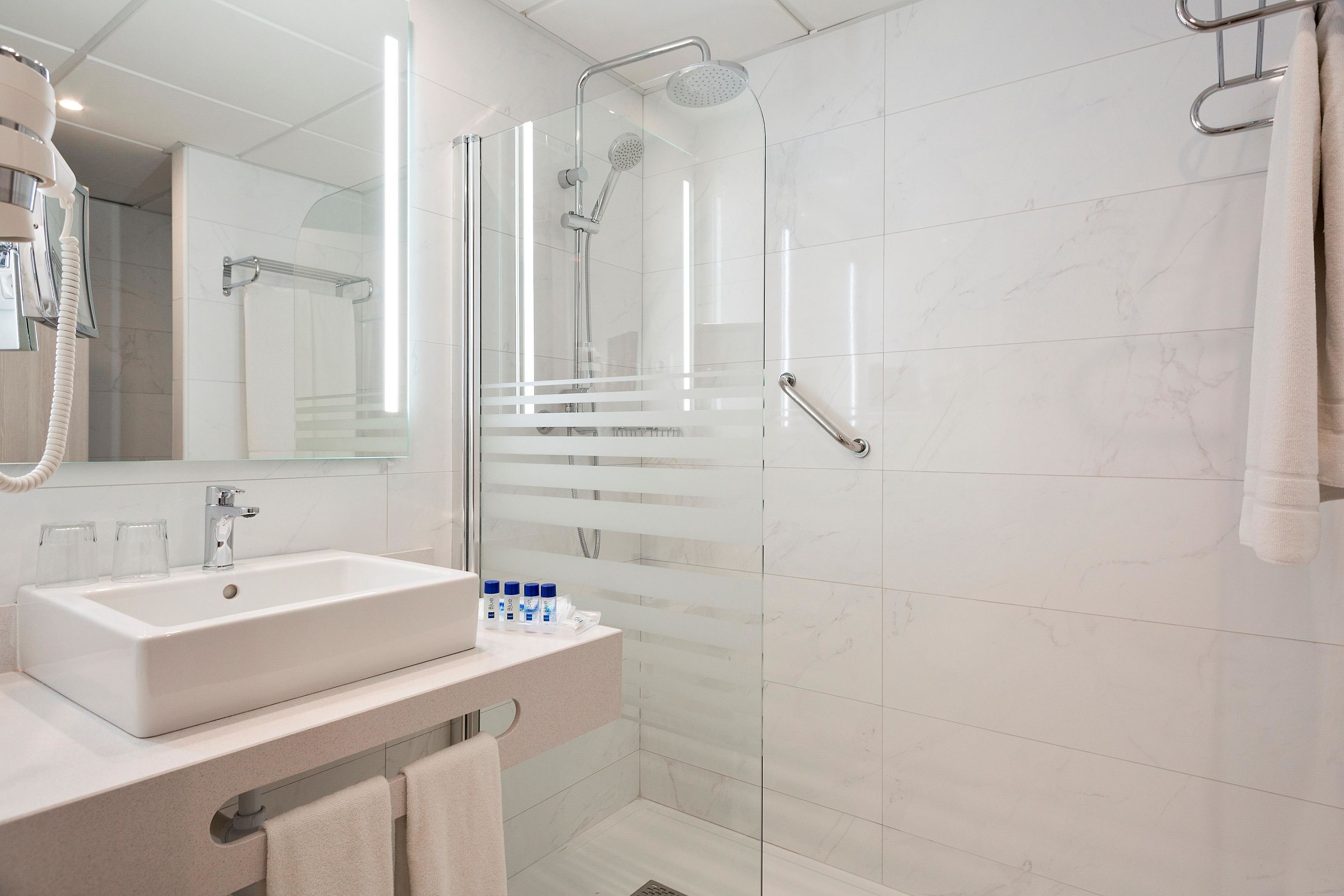 A modern bathroom with a glass-enclosed shower, a white sink, and a mirror.