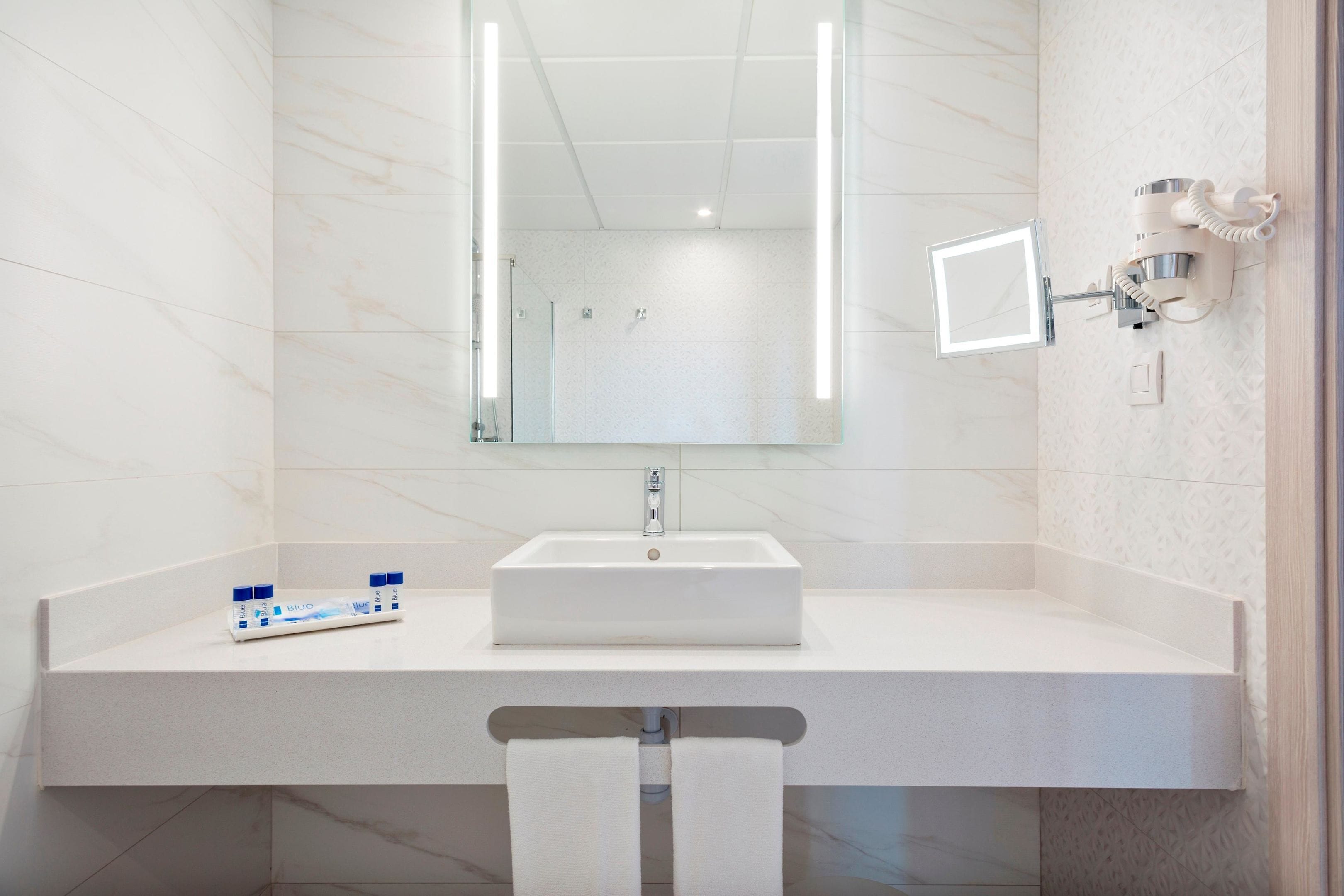 A bathroom with a white sink, a mirror, and a towel rack.