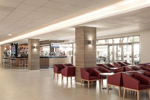 A self-service area with a counter, seating area with chairs, and a view of the outside through large windows. - Hotel Best Oasis Park (Salou)