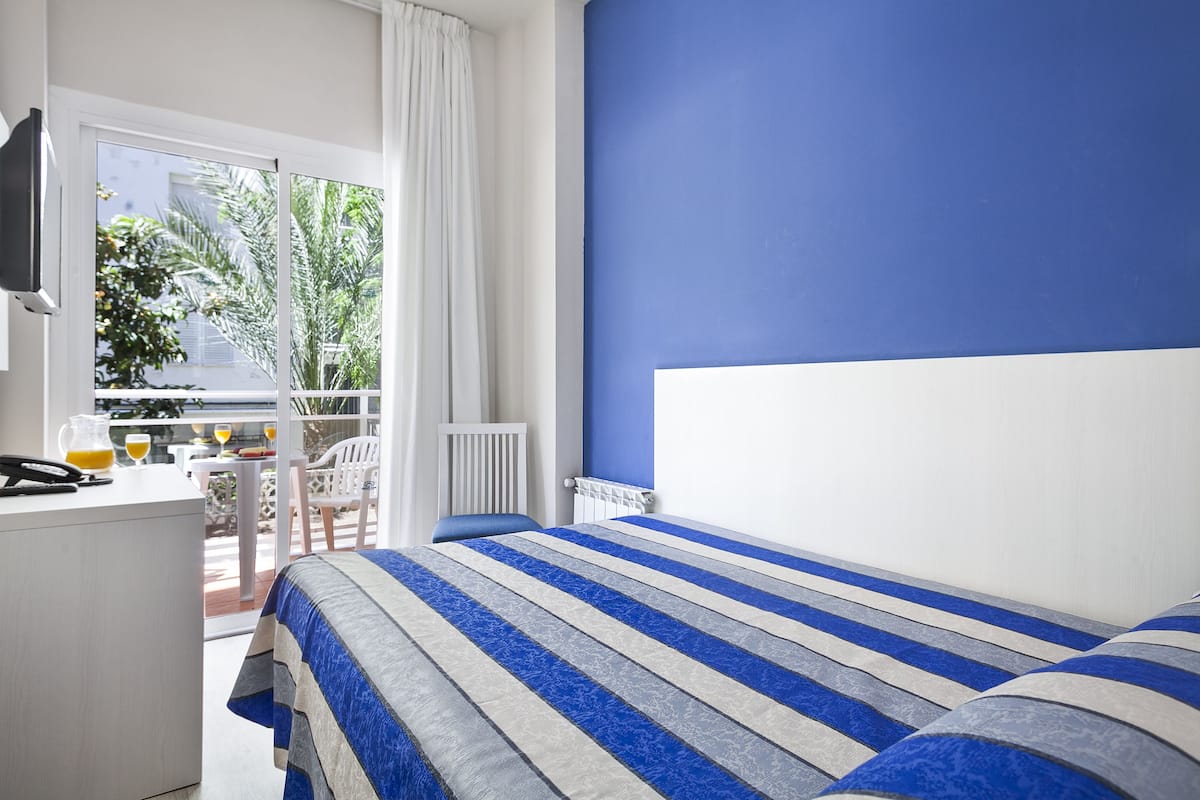 Une chambre avec un lit, un bureau et une vue sur l’extérieur.