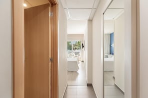 A hotel corridor with a wooden door, a white wall, and a view of a balcony with outdoor furniture. - Hotel Best Oasis Park (Salou)