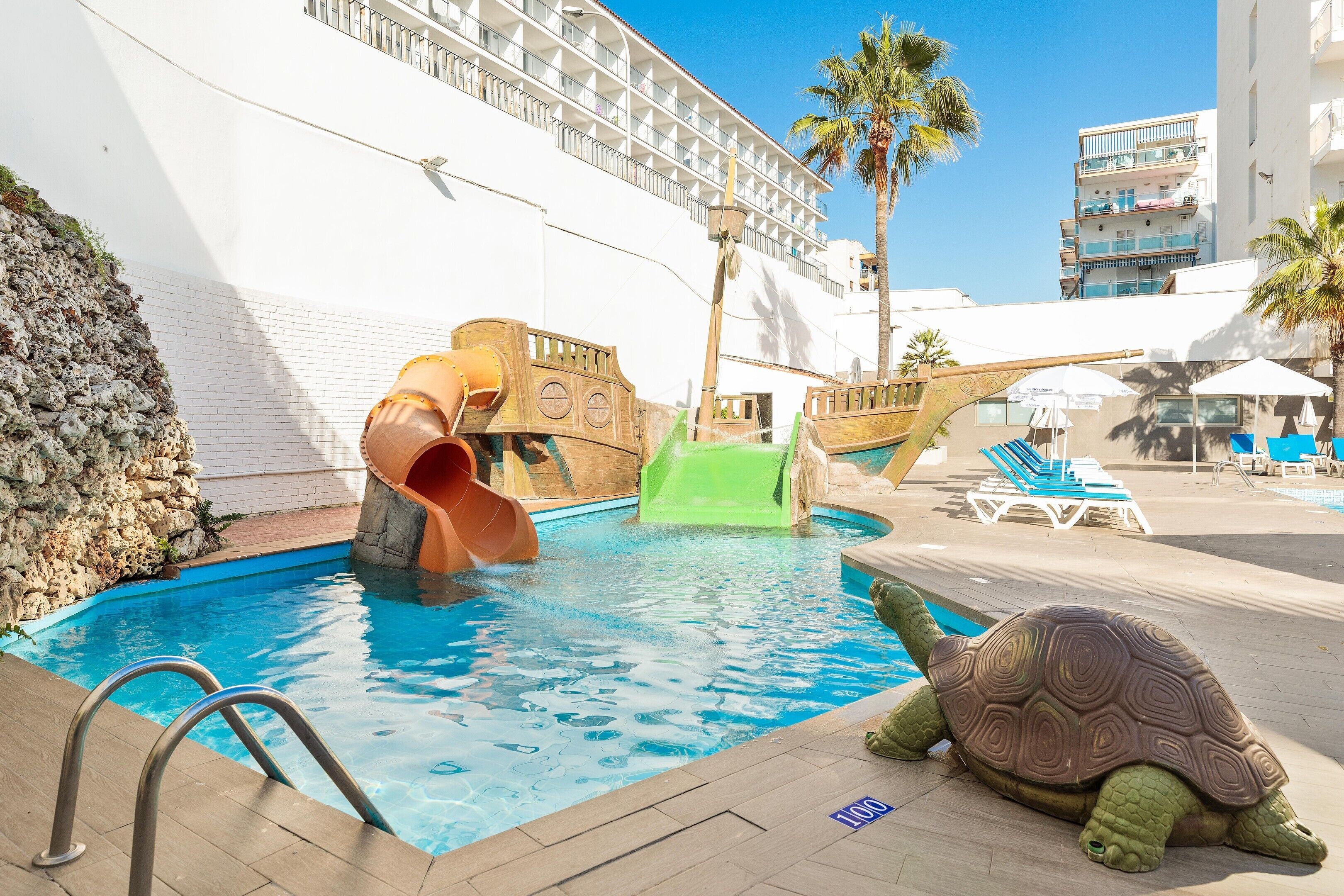 A swimming pool with a slide and a turtle decoration.