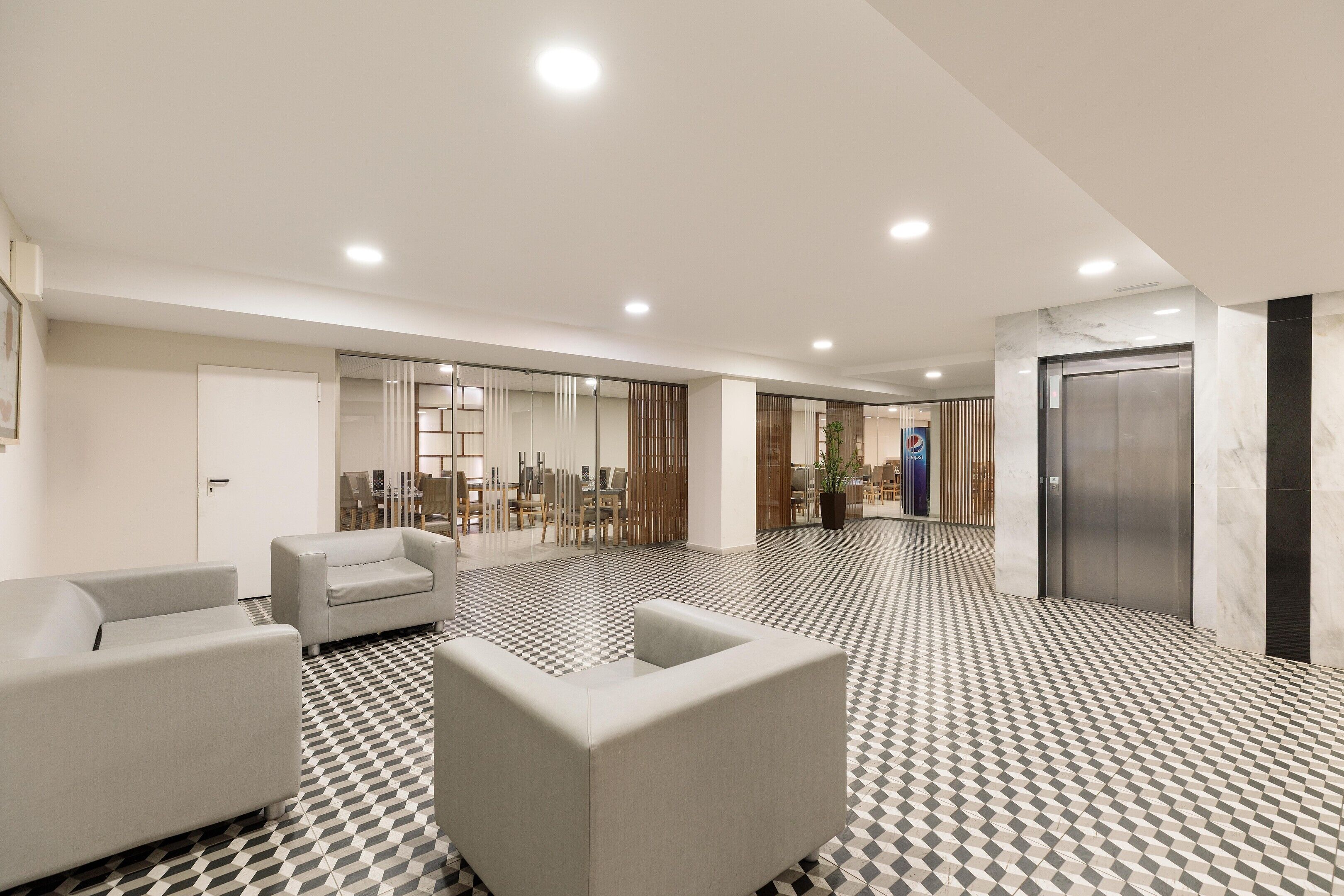 A modern lobby with a checkered floor, seating area, and an elevator.