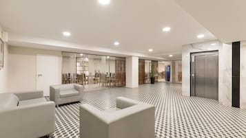 A modern lobby with a checkered floor, seating area, and an elevator.