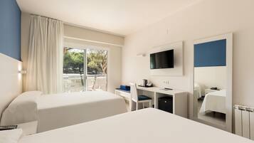 Habitación de hotel con cama, escritorio, silla, televisor y ventana con cortinas.