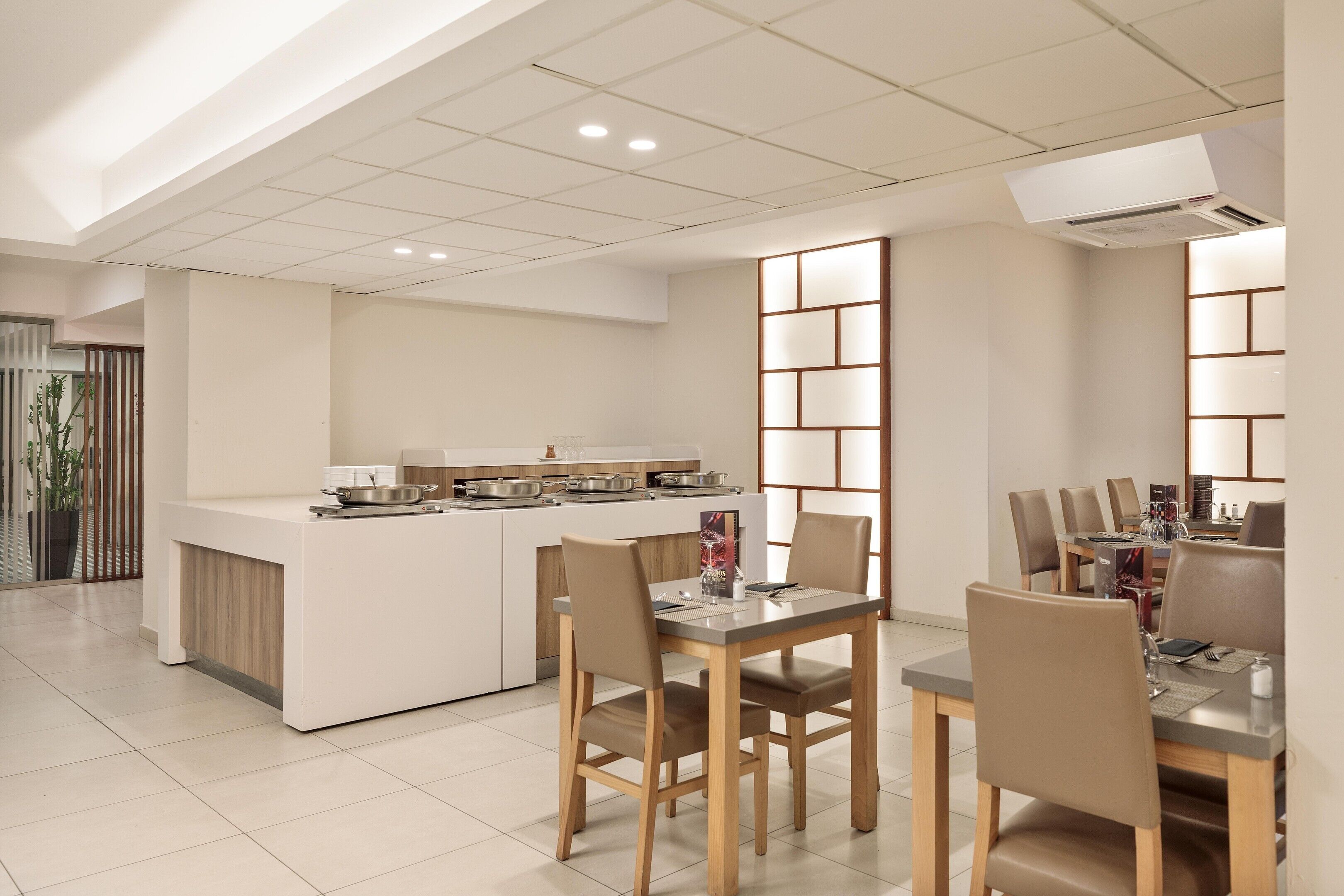 Una cocina moderna con una isla central, comedor con sillas y vistas al exterior.