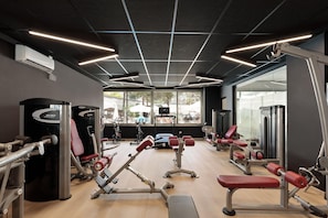 A gym with various exercise equipment, large windows, and a modern ceiling design. - Hotel Best Oasis Park (Salou)