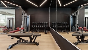 A gym with exercise equipment, weight racks, and mirrors. - Hotel Best Oasis Park (Salou)