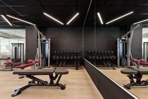 A gym with exercise equipment, weight racks, and mirrors. - Hotel Best Oasis Park (Salou)