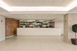 Ett välkomnande område med modern design, bestående av en receptionsdisk, en digital skärm och en växt.