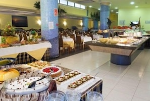 Un montaje tipo bufé con diversos alimentos y una zona de estar con mesas y sillas.