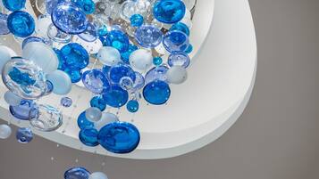 A cluster of transparent glass spheres in various sizes and shades of blue and white, suspended in mid-air.