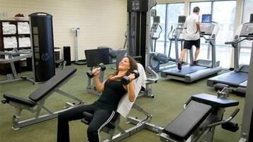 Une salle de sport équipée de matériel d’exercice, notamment un banc de développé couché, des haltères et des tapis de course.