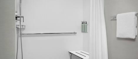 Une salle de bain moderne équipée d’une douche, d’un porte-serviettes et d’une petite table.