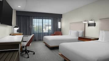 Een hotelkamer met twee bedden, een bureau, een stoel en een televisie.