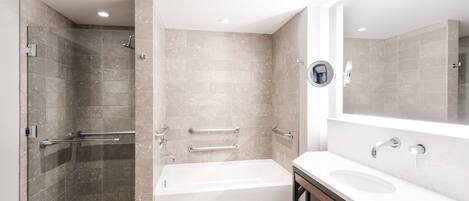 Un baño moderno con ducha envuelta en cristal, una bañera independiente y un tocador con lavabo y espejo.