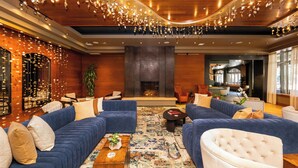 A spacious lobby with a large seating area, a fireplace, and a modern ceiling design.