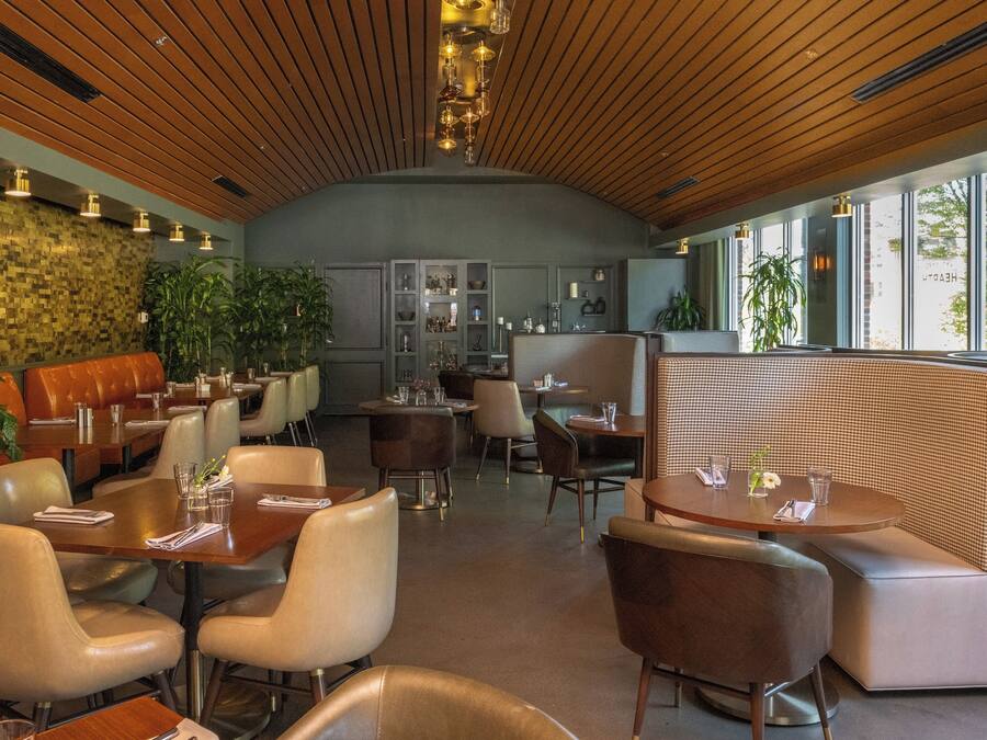Un restaurante moderno con techo de madera, asientos acolchados y ventanas amplias.