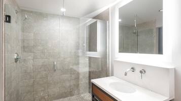 A modern bathroom with a glass-enclosed shower, a white sink, and a large mirror.
