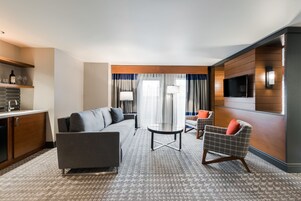 Una habitación de hotel moderna con sofá, sillón y una pequeña mesa.