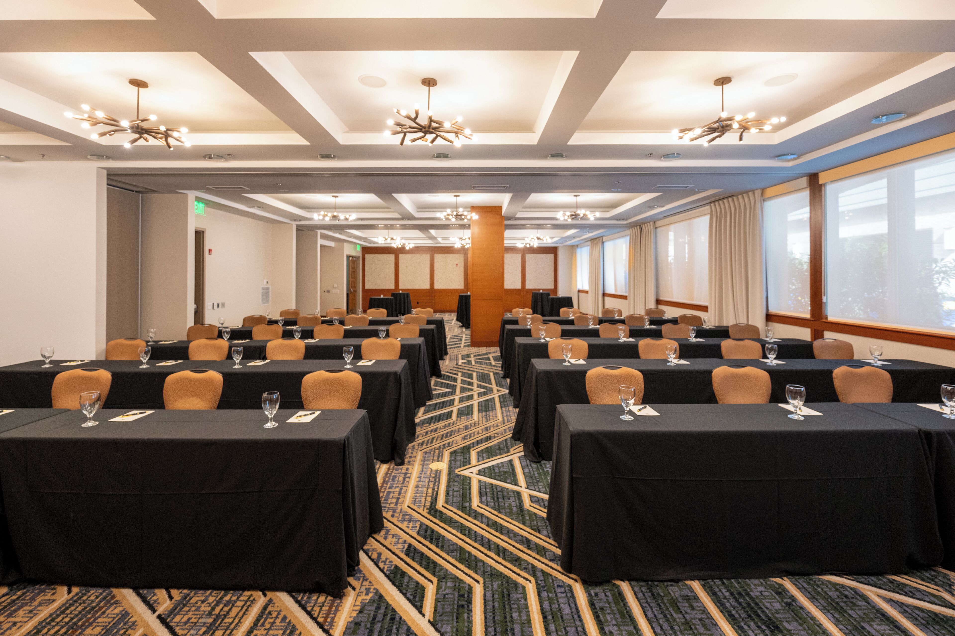 A conference room with multiple tables, chairs, and a patterned carpet.