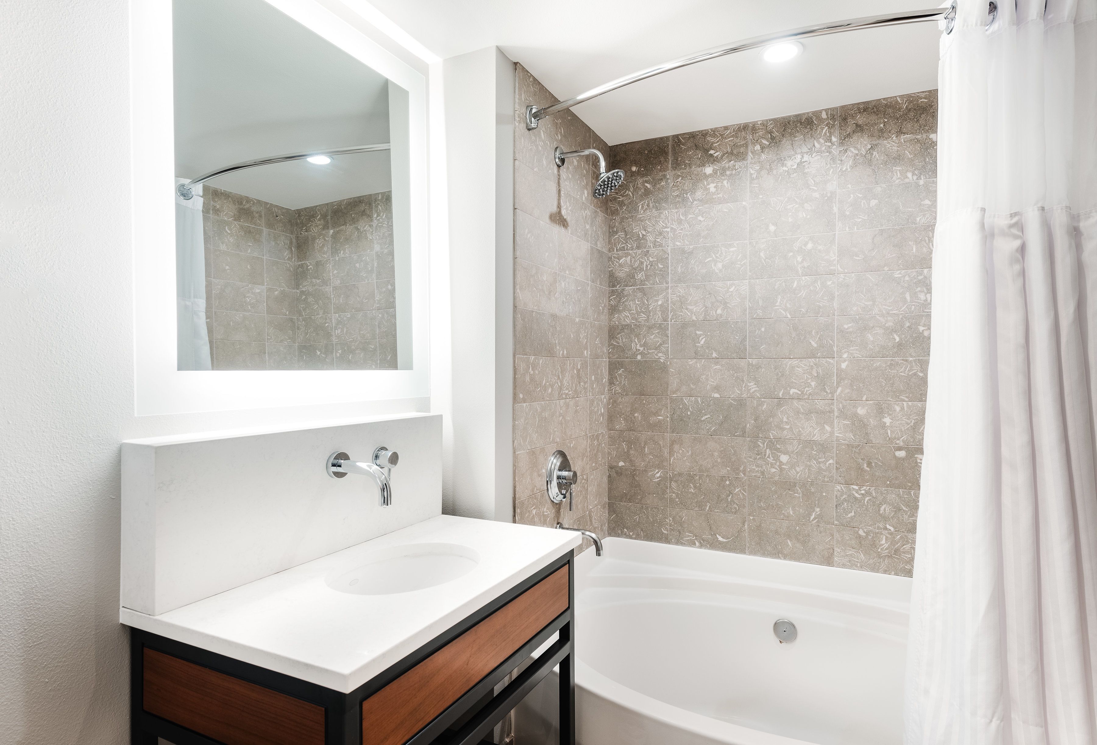 Un baño moderno con tocador doble, ducha con puerta de vidrio curva y bañera.