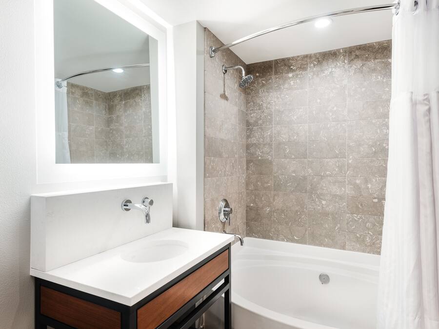 Ein modernes Badezimmer mit einem Doppelwaschtisch, einer Dusche mit gebogener Glastür und einer Badewanne.