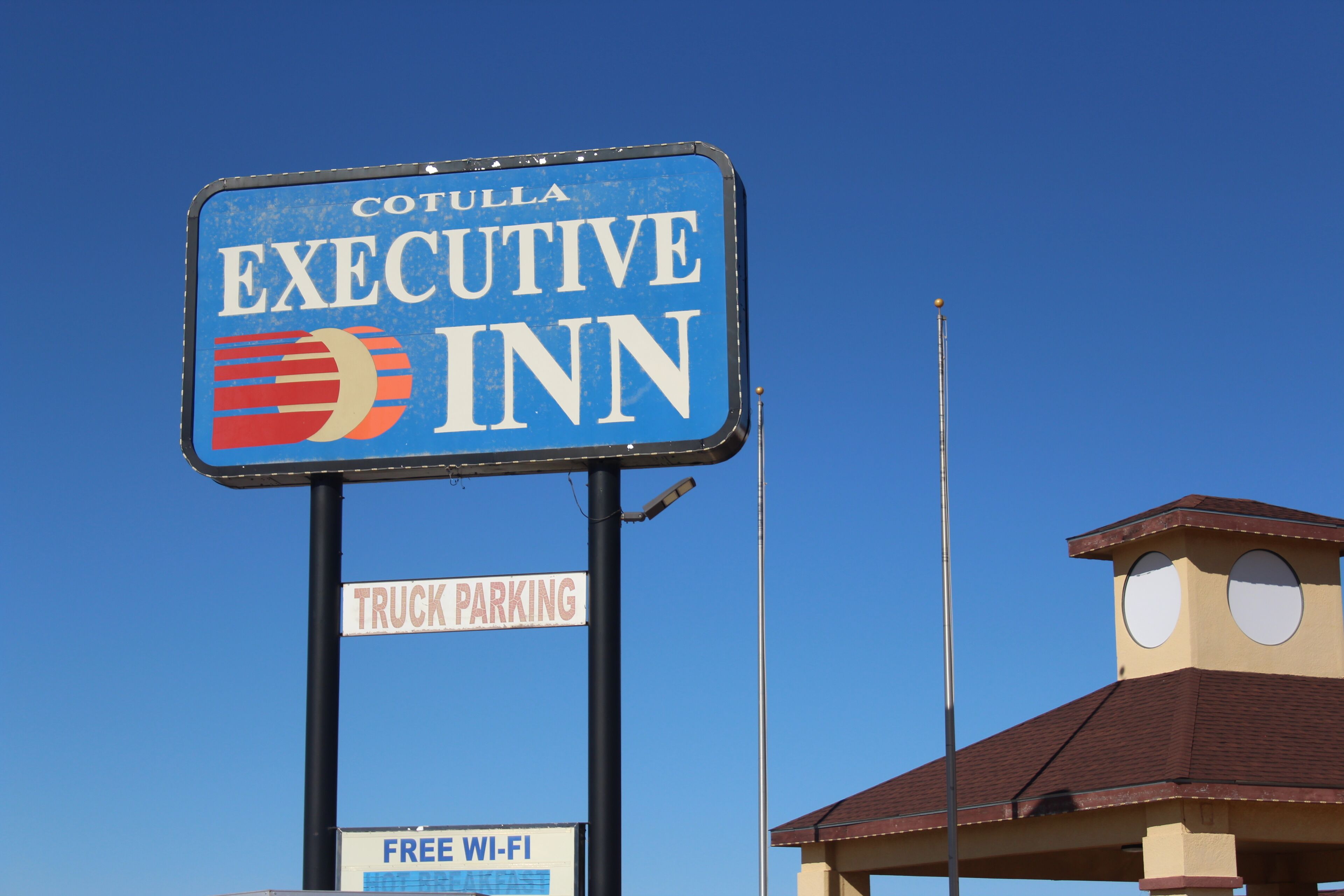 A sign for Cotulla Executive Inn with a truck parking sign and a free Wi-Fi sign.