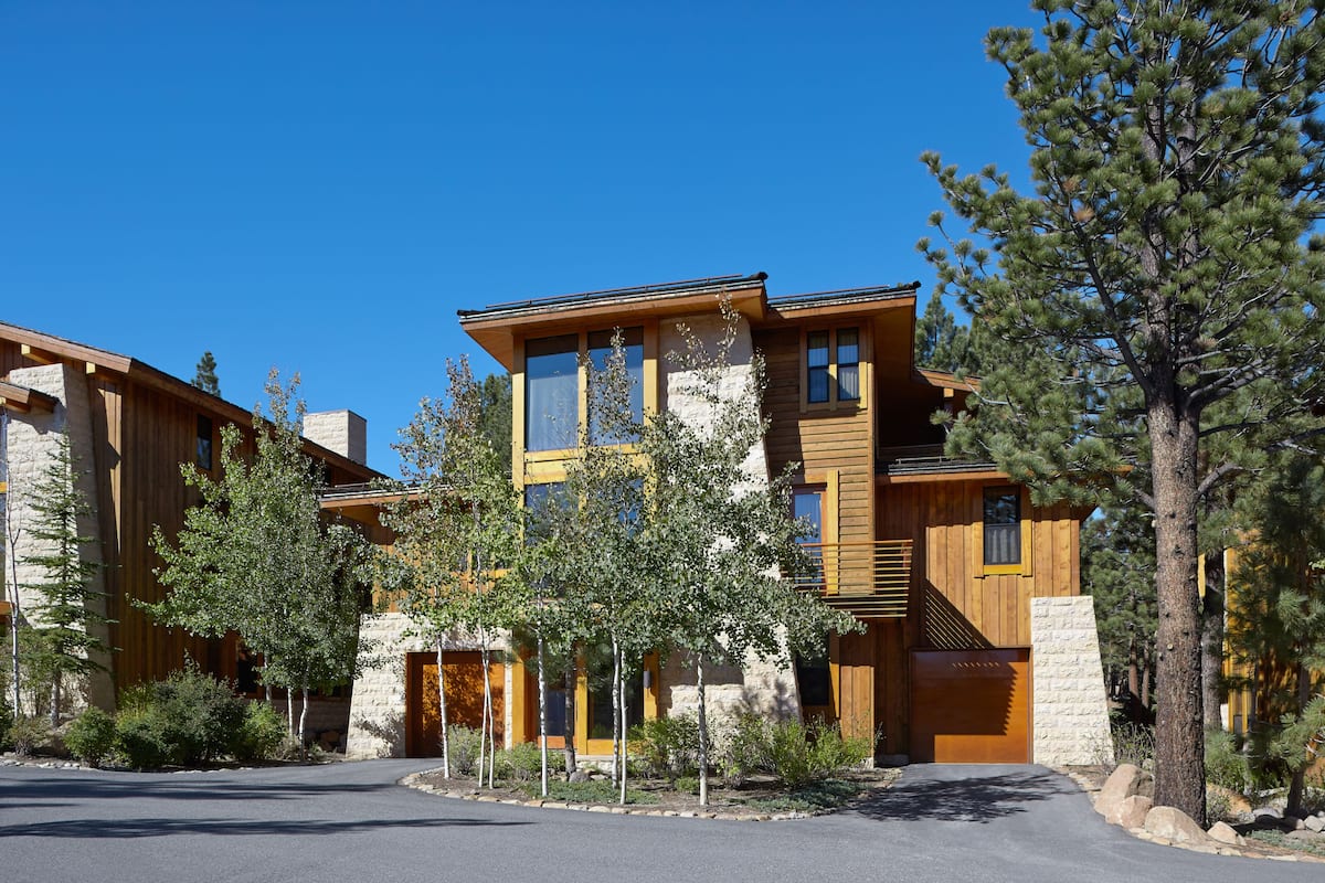 A modern multi-story house with a stone facade, large windows, and a wooden exterior.