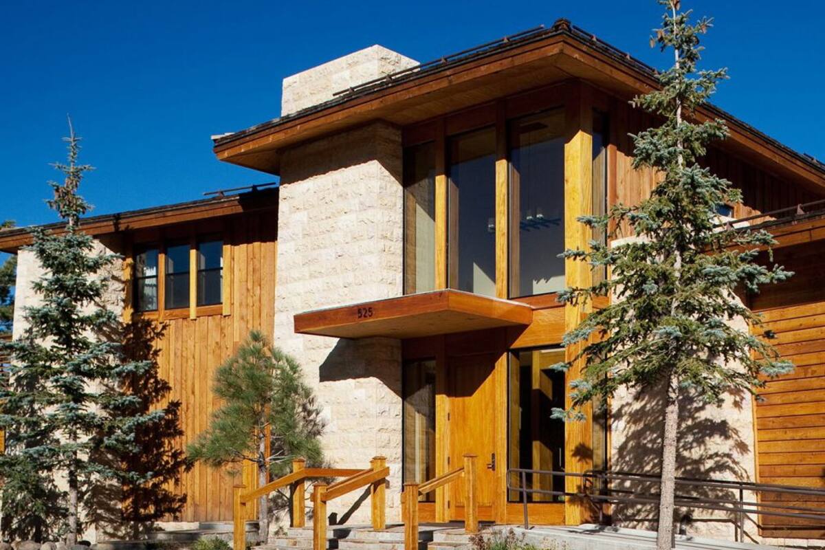 A modern building with a stone facade, large windows, and wooden accents.